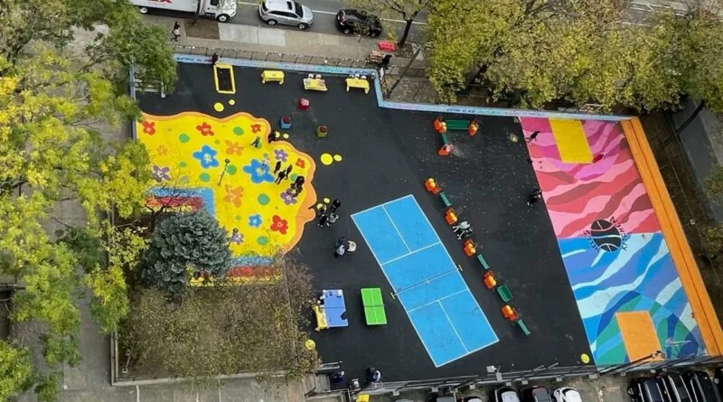 Aerial view of the transformed Harborview Terrace play area, with a blue court, colorful asphalt art and a flower-painted play surface
