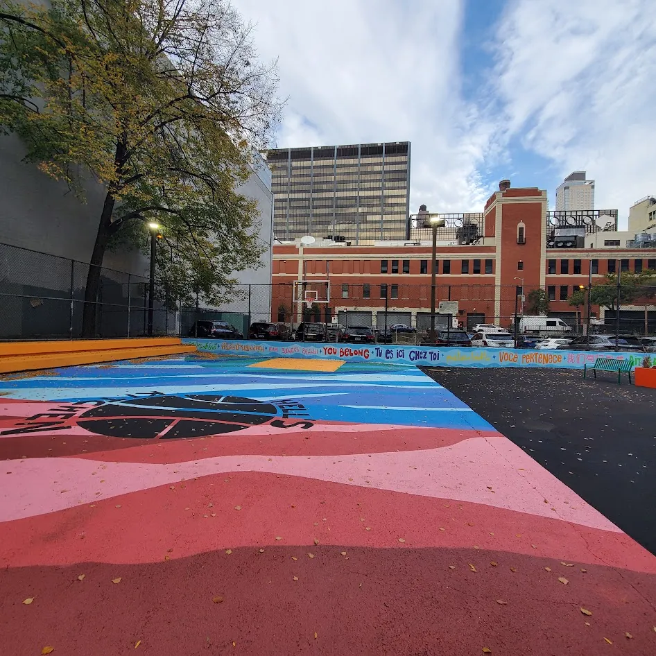 Ground-level view of the Harborview Terrace court, painted in pink and blue waves, with You Belong written in many languages along the wall